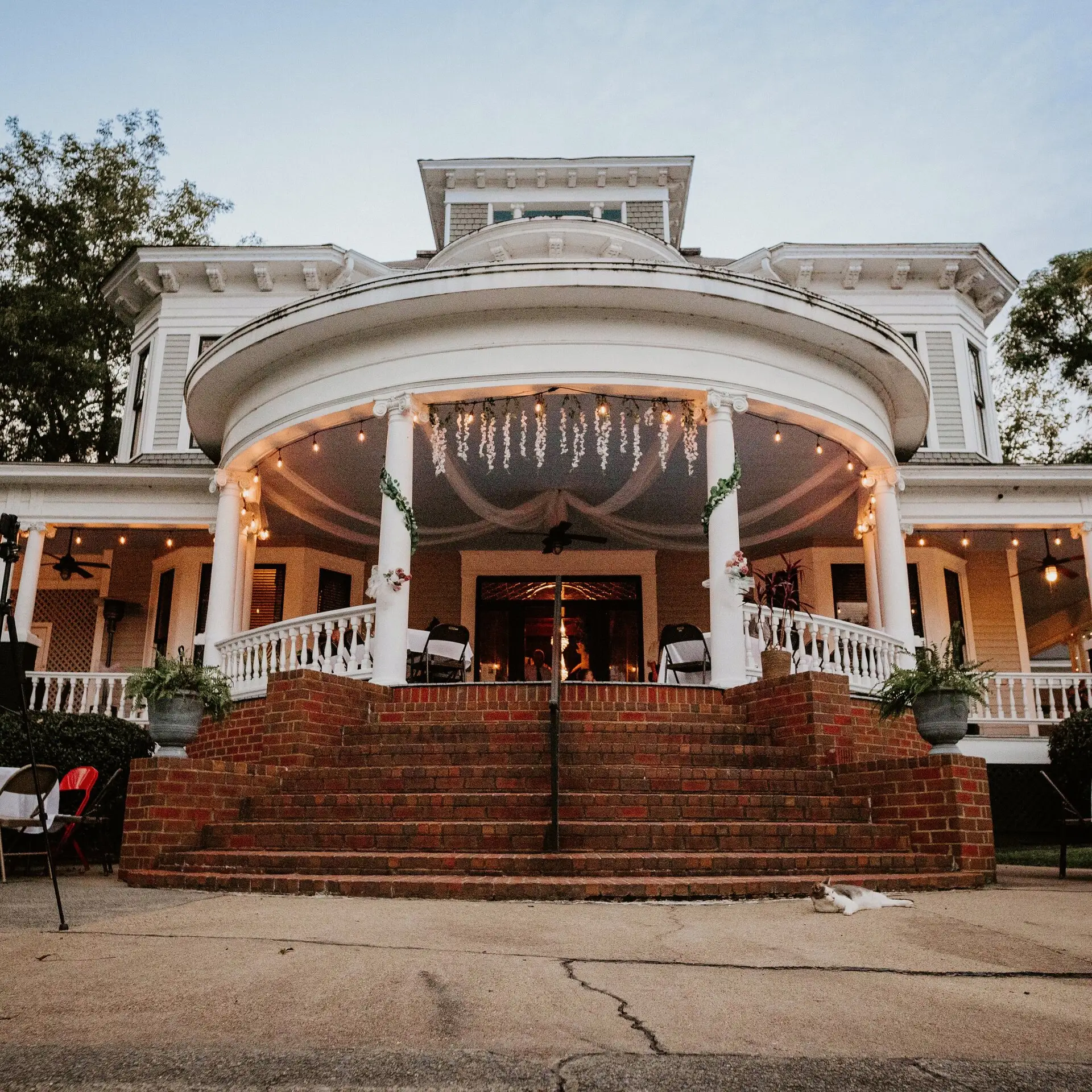 The wraparound porch decorated for an event at dusk
